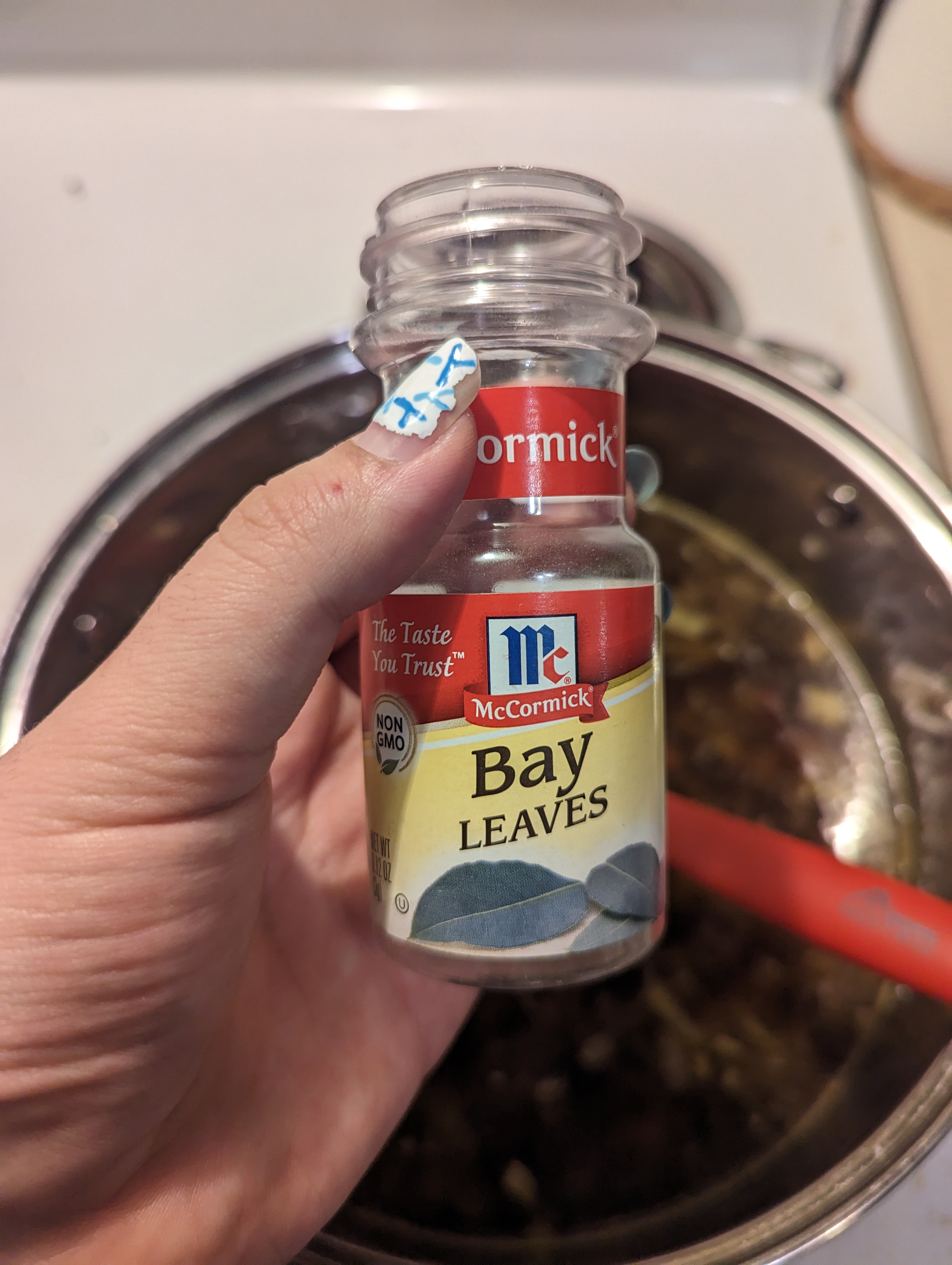 A bottle of bay leaves held above the stew